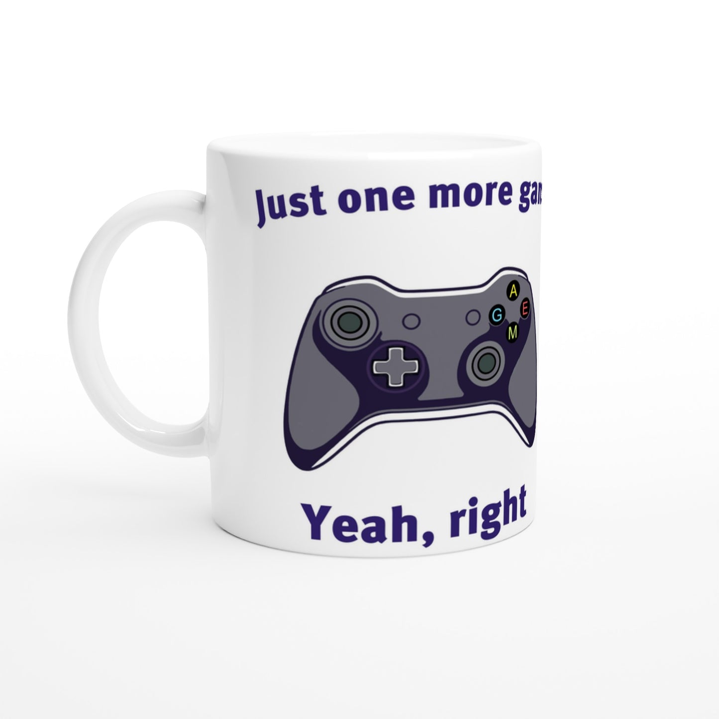 White coffee mug. Xbox-style game controller in the middle
At the top are the words, "Just one more game" in dark blue.
At the bottom are the words, "Yeah, right" in dark blue.